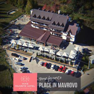 ein großes Gebäude mit Autos auf einem Parkplatz in der Unterkunft Mia's Favorite Hotel in Mavrovo-Nationalpark