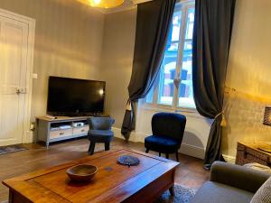 la Porte aux Dames في رومورانتا: غرفة معيشة مع تلفزيون وطاولة وكراسي