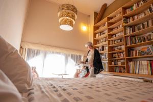 a woman standing next to a bed in a library at B&B A Quiet Place in Rossignol