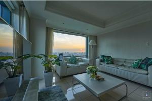 ein Wohnzimmer mit Sofas, einem Tisch und einem großen Fenster in der Unterkunft Corner Inn in Taichung