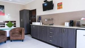 a kitchen with a sink and two chairs and a bed at Nahoon Eco Lodge on Mackenzie in East London