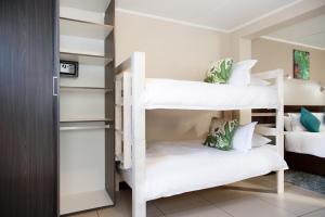 1 dormitorio con 2 literas con almohadas blancas en Nahoon Eco Lodge on Mackenzie, en East London