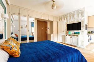 a bedroom with a blue bed and a tv at Apartamenty na Roztoczu - Apartament Szafirowy in Zamość