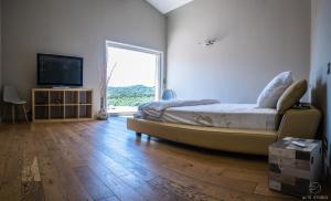 a bedroom with a bed and a television on a wooden floor at Casa Lagone - Villa avec Piscine et Superbe Vue in Cargèse