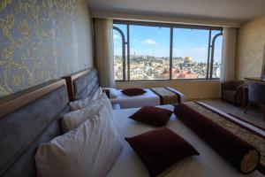 a hotel room with two beds and a large window at Hashimi Hotel Old City Jerusalem in Jerusalem