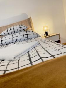 uma cama com lençóis pretos e brancos e um candeeiro em City Center Apartman Miskolc em Miskolc