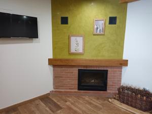 a living room with a brick fireplace and a flat screen tv at Valle del sol I in Pajares