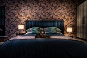 un gatto seduto su un letto in una camera da letto di Broomhill Estate Boutique Art Hotel a Barnstaple