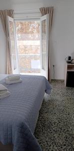 a bedroom with a bed and a large window at Argonaftis Spetses in Spetses