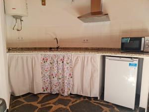 a kitchen counter with curtains and a sink at Chozos Las Flores de la Dehesa in Calzadilla