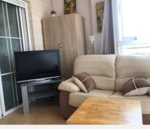 salon z kanapą i telewizorem z płaskim ekranem w obiekcie Apartamento con 2 stanze letto w mieście Torrevieja