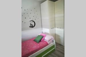 a small bedroom with a bed with pink and green pillows at Apartamento en ribeira sacra. Chantada in Chantada