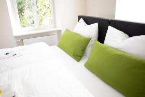 a bedroom with a white bed with green pillows at villaflora Gästehaus in Riedlingen