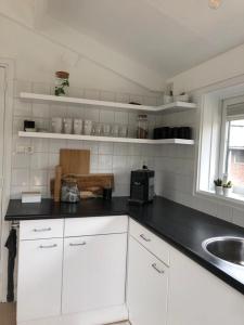 a kitchen with white cabinets and a black counter top at Kust-, fiets-, wandel-, rust- & cultuurlocatie in Castricum