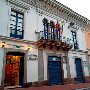 un edificio blanco con 2 banderas en un balcón en Casa Hotel Las Plazas, en Quito