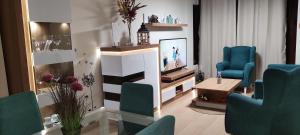 un salon avec des chaises bleues et une télévision dans l'établissement Apartamento El Juncal Parking gratuito, à Cabra