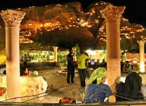 un grupo de personas de pie alrededor en un parque por la noche en Seven Wonders Bedouin Camp en Wadi Musa