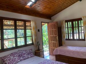 una camera da letto con letto, finestre e soffitto in legno di Chalé Hakuna Matata a Lumiar