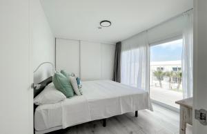 a white bedroom with a bed and a large window at Island Home Fuerteventura in Corralejo