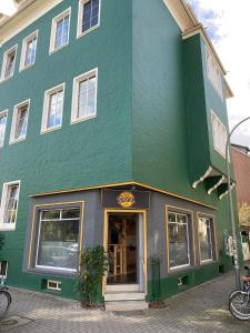 un grand bâtiment vert avec un magasin dans l'établissement Jonnys Loft, à Osnabrück