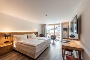 Habitación de hotel con cama, escritorio y TV. en Naco Aparthotel, by Arca Solebad, en Zermatt