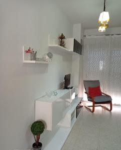 a white living room with a chair and a television at Disfruta Granada,incluso con tu mascota Parking in Granada