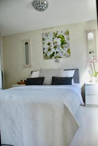 1 dormitorio con 1 cama blanca grande y 2 cuadros en la pared en Charmant chalet op een bospark op de Veluwe, en Putten