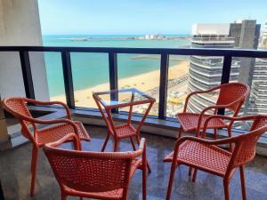 uma varanda com cadeiras, uma mesa e uma praia em Hotel Flat Atlântico em Fortaleza