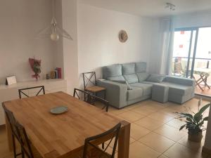 ein Wohnzimmer mit einem Tisch und einem Sofa in der Unterkunft Playa Valencia Residencial Sol y Mar Terraza con Vistas y Parking in Playa Pobla de Farnals