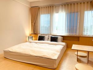 a bedroom with a large white bed in front of a window at Ma-TaÔ またお Café & hostel in Nan