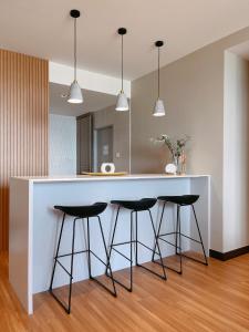 a kitchen with a large white counter with three bar stools at SURAI Homes in Kuala Terengganu