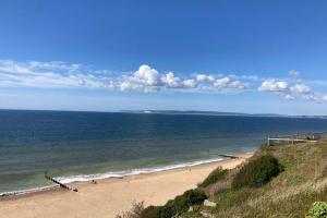 a beach with people on the sand and the ocean at New apartment within short walk of the beach in Southbourne