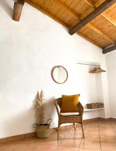 silla de mimbre en una habitación con espejo en Is Scabas Guestrooms, en Solarussa