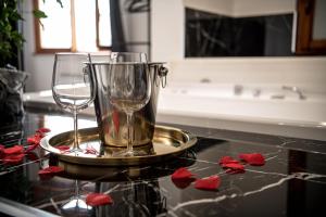 two wine glasses on a tray on a counter with roses at CS LUXURY HOUSE in Lido di Ostia