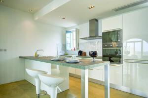 uma cozinha com um grande balcão com dois bancos brancos em FIFTY-FOUR Edge Pool House - GOZO em Il-Pergla