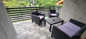 un patio con 2 sillas, una mesa y una barandilla en Comfort Home Apartment 3, en Petroşani