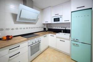 a kitchen with white cabinets and a blue refrigerator at Apartamento Boutique Plasencia Centro in Plasencia