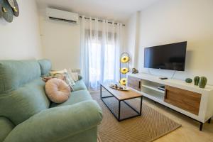 a living room with a blue couch and a tv at Apartamento Boutique Plasencia Centro in Plasencia