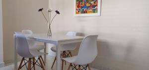 een witte tafel met witte stoelen en een vaas met bloemen bij Apartamento nuevo playa de Canet de Berenguer WIFI in Canet de Berenguer