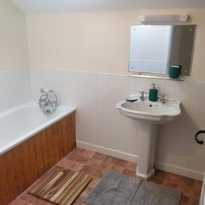 a bathroom with a sink and a bath tub and a mirror at Marsland Cottage in Bideford