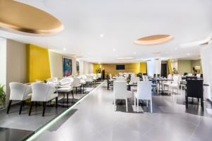 un restaurante con mesas blancas y sillas blancas en Hotel American Golf, en Barranquilla