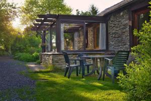 a table and chairs in front of a stone house at La Petite Maison in Six Planes