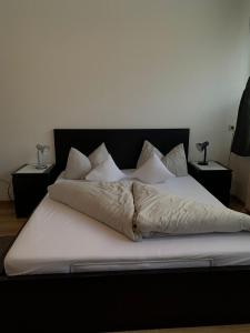 1 cama grande con sábanas blancas y almohadas. en Ferienwohnung Schweng en Tux