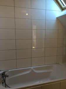 a white tiled bathroom with a bath tub at Gite des 3 cigognes in Colmar +27 photos
