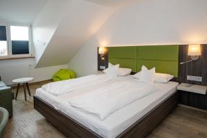 a bedroom with a large white bed with a green headboard at Insel-Hotel-Lindau in Lindau