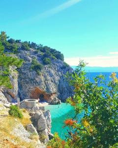 a beach on a cliff with people in the water at Studio-Apartman-Diana in Brseč