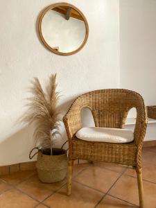 a wicker chair sitting in a room with a mirror at Is Scabas Guestrooms in Solarussa