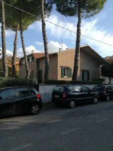 zwei Autos, die vor einem Haus mit Palmen geparkt sind in der Unterkunft AFFITTACAMERE VILLA SOFIA accanto Ospedale con ampio giardino in Fano