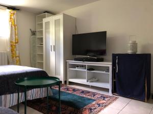 a bedroom with a tv and a bed and a table at Room in house near Lycee International St Germain en Laye in Saint-Germain-en-Laye