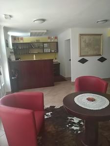 ein Wohnzimmer mit 2 roten Stühlen und einem Tisch in der Unterkunft Depandansa Hotel-a Pri Belokranjcu in Metlika
